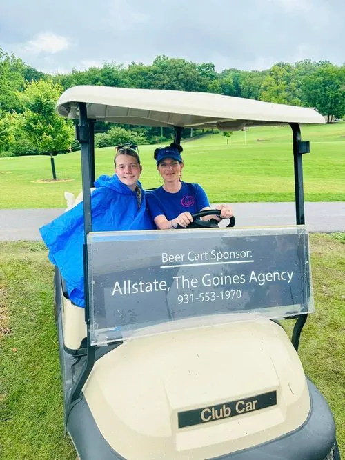 Alexis Goines and a young member of the Goines Agency family keep the golf-cart fun rolling at a community fundraiser.