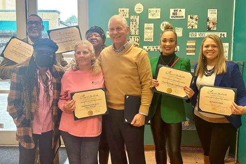 A room full of smiles as community members receive certificates of achievement.